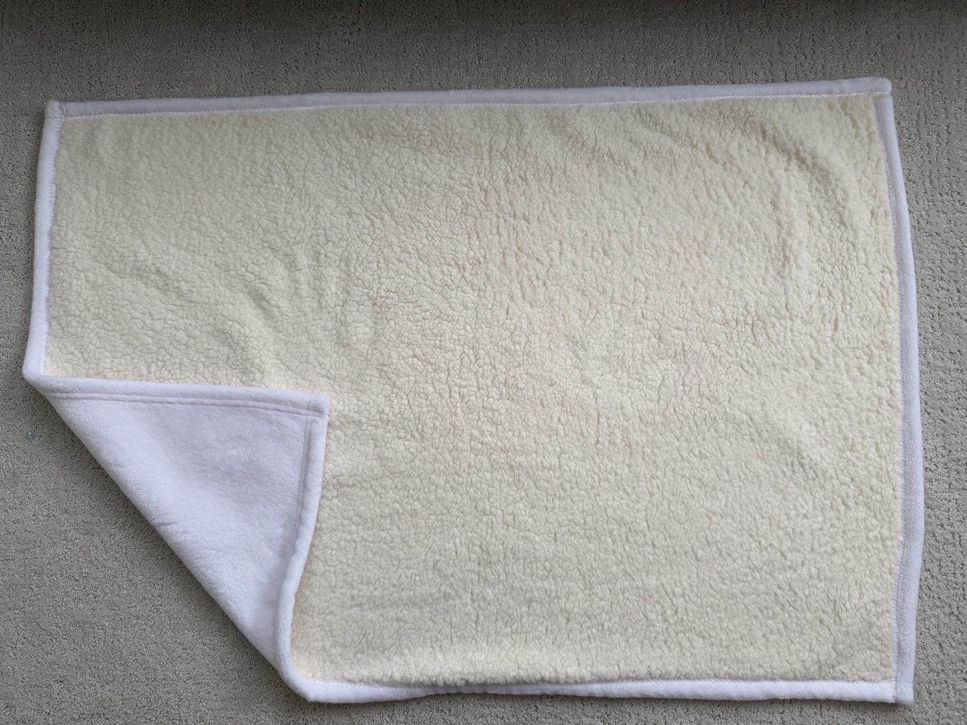 Bound-edge sherpa blanket with one corner folded back to show the white flannel print face