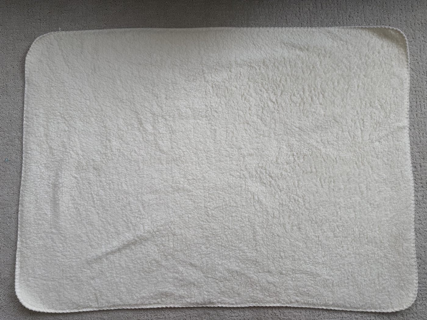 Overlocked sherpa blanket with rounded corners, sherpa side facing up