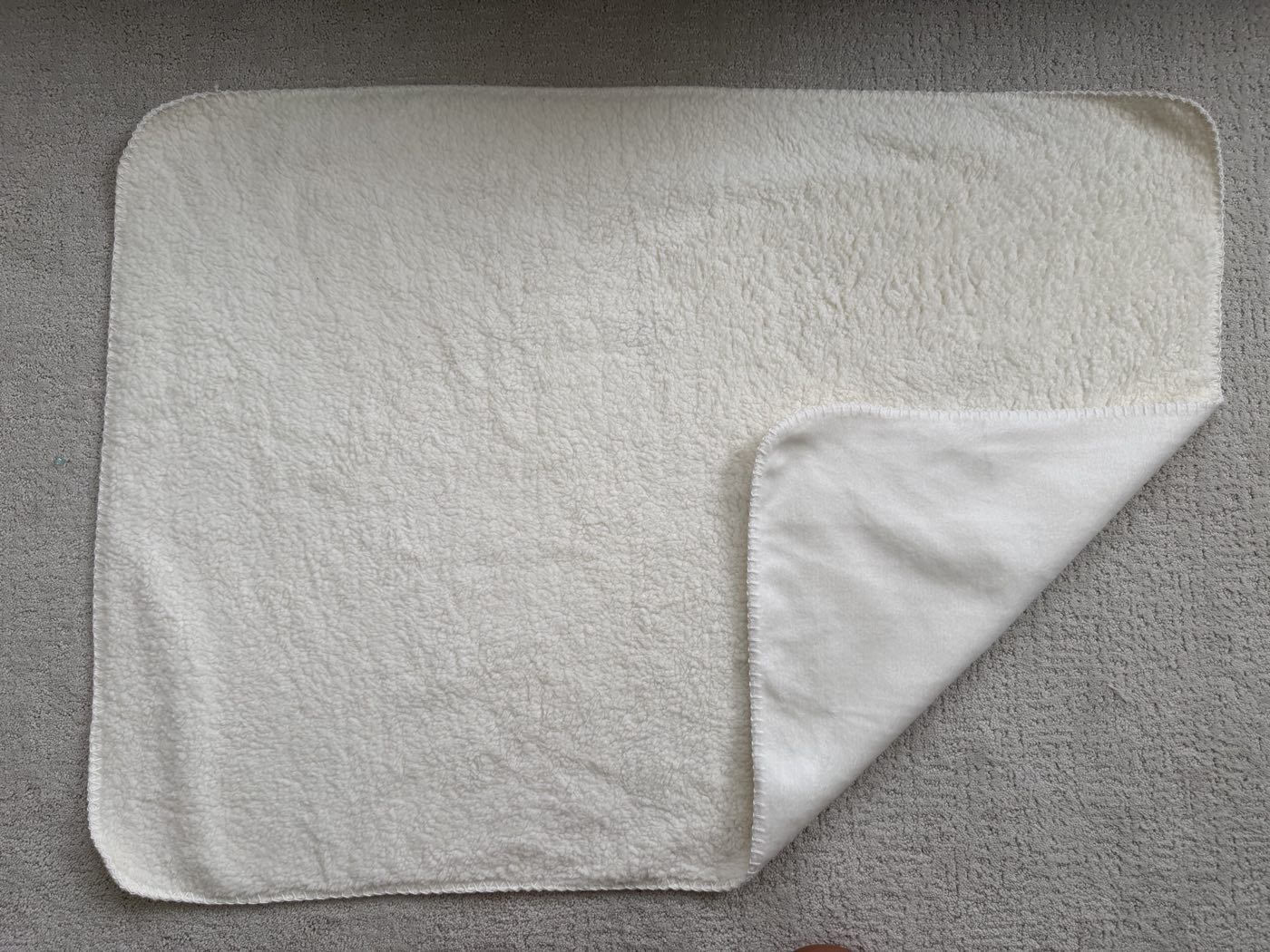 Overlocked sherpa blanket with rounded corners, folded back to show the polar fleece print face